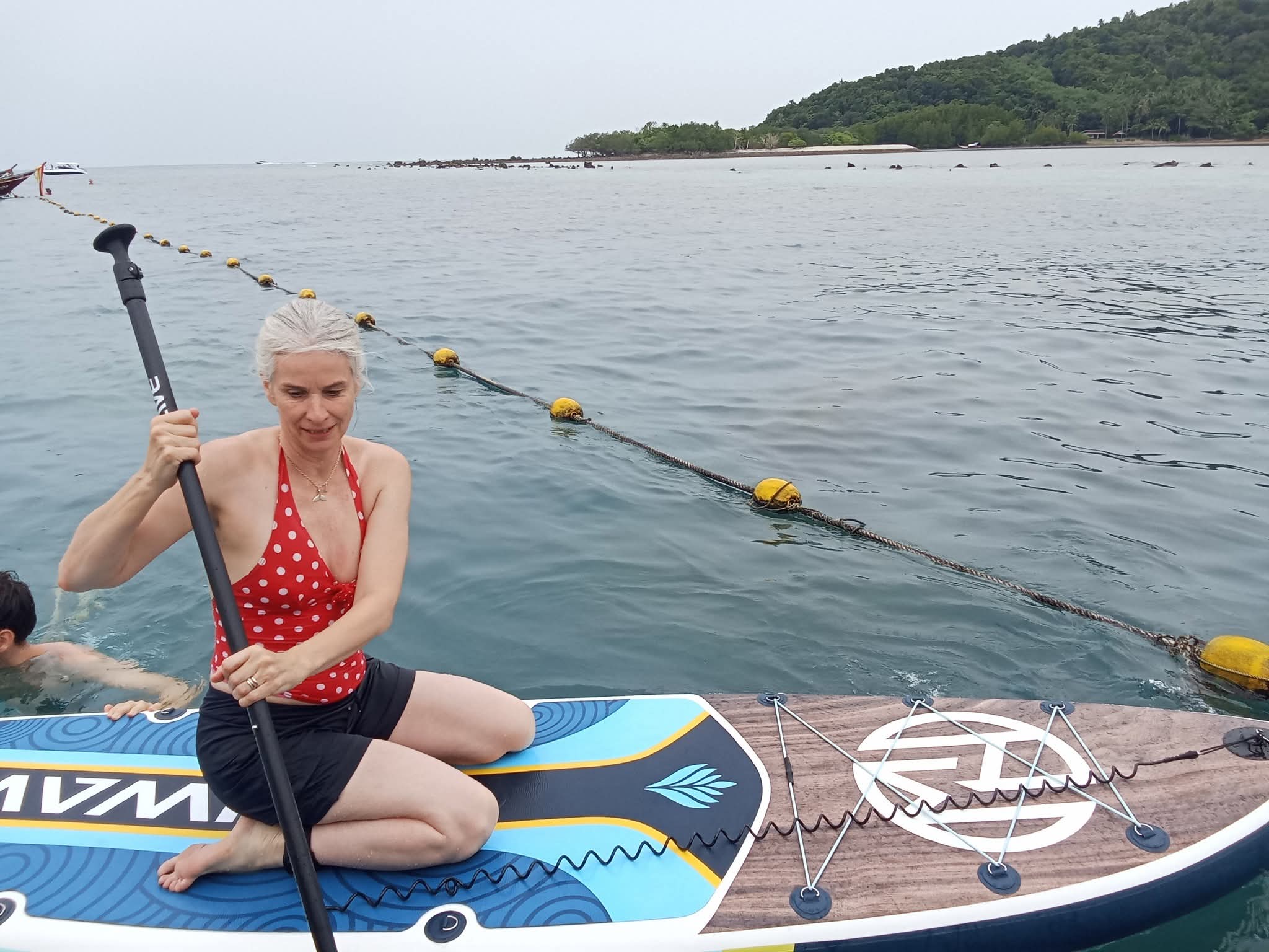 Guest stand-up paddleboarding on the Electric Long-tail Eco Tour