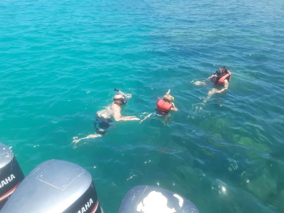 Guests snorkeling in turquoise water beside the tour boat
